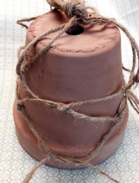 Vänd på krukan
Ställ krukan upp och ner, lägg knuten mitt på krukan. Fördela snören jämnt runt krukan.