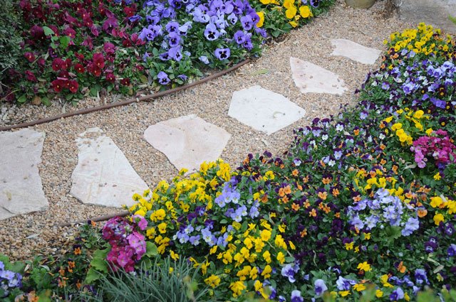 Plattor och grus på gångar eller under utemöbel blir ett tåligt golv i trädgården. Kontrasten mellan den hårda ytan i neutral färg och blommiga planteringar, som väller ut över ”golvet”, gör dessutom att växtligheten framhävs ytterligare.