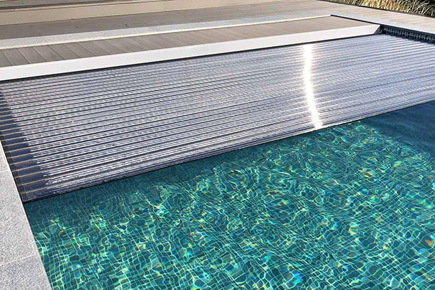 Stilrent och praktiskt! Ett lamelltäcke med appstyrning klarar hundra kilos tyngd. Foto: Poolgiganten