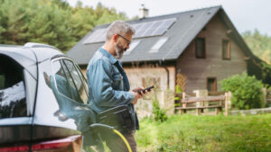 Man framför elbil och hus med solceller
